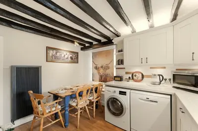 a kitchen with a table and chairs and a washer at Walthwaite How Cottage in Chapel Stile
