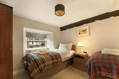 a bedroom with two beds and a window at Walthwaite How Cottage in Chapel Stile