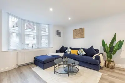 a living room with a blue couch and a table at Stone Street Modern 3-Bed for Groups & Families in Broughton