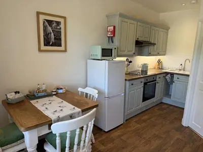 a kitchen with a table and a white refrigerator at The Cottage in Keswick