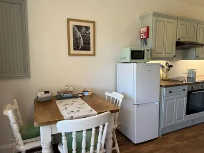 a kitchen with a table and a white refrigerator at The Cottage in Keswick