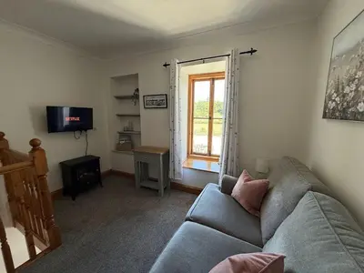 a living room with a couch and a window at The Cottage in Keswick