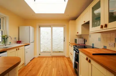 a kitchen with white cabinets and a large window at Moir Cottage in Portpatrick