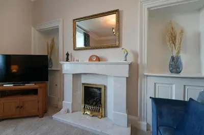 a living room with a fireplace and a mirror at Mariners Haven in Troon in Troon