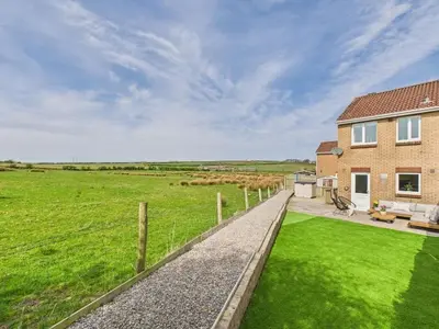 a house with a green field and a fence at The Haven Holiday Home in Woodend