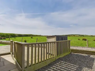 a wooden fence with a view of a field at The Haven Holiday Home in Woodend