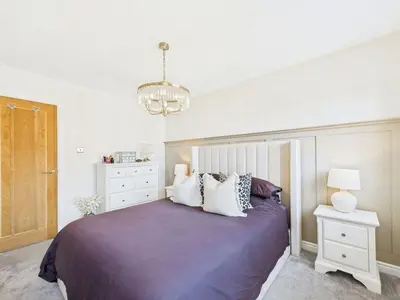 a bedroom with a bed and a chandelier at The Haven Holiday Home in Woodend
