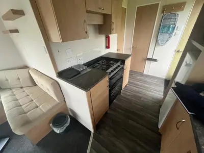 a small kitchen with a stove and a couch in a caravan at MaCEIDEIRD in Mainsriddle