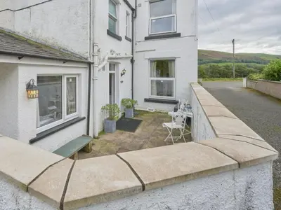 a patio outside of a white house with a table at 2 Bed in Cockermouth oc-sz431 in Bassenthwaite Lake