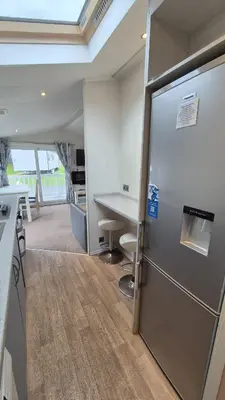 a kitchen with a stainless steel refrigerator and a table at Caravan Bliss in Minishant