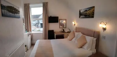a bedroom with a bed and a desk and a window at Dunsford Guest House in Keswick