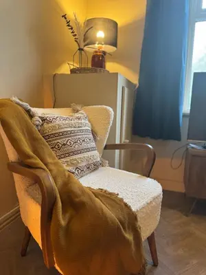 a living room with a chair with a blanket on it at Central Carlisle Modern 4BD w Wi-Fi, Washer, & SmartTVs, close to M6 in Carlisle