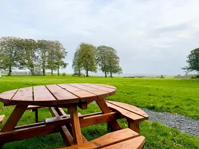 a wooden picnic table in a field of grass at Wild Meadow Cottage - Countryside Views and King Bed in Maybole
