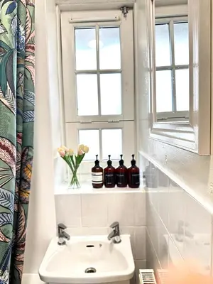 a bathroom with a sink and a window with bottles on a shelf at Entire 1 bedroom in VAUXHALL Central London Zone 1 in Moffat