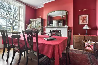 a red dining room with a table and a mirror at Seaside ParkView Near Lake District and Marina - Pass the Keys in Whitehaven