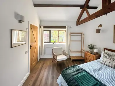 a bedroom with a bed and a chair and a window at Lime Tree Barn in Tallentire