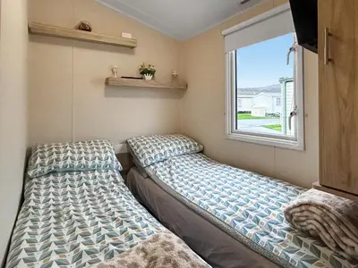 two beds in a small room with a window at Ali B's Craig Tara in Ayr