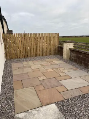 a patio in front of a wooden fence at Cross Beck Cottage in Allonby