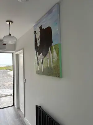 a painting of a cow hanging on a wall at Cross Beck Cottage in Allonby