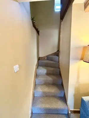 a stairway in a house with a blue carpet at Maggies Cottage in Little Broughton