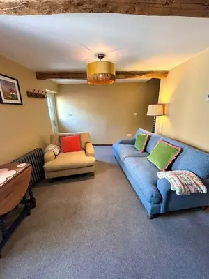 a living room with two couches and a table at Maggies Cottage in Little Broughton