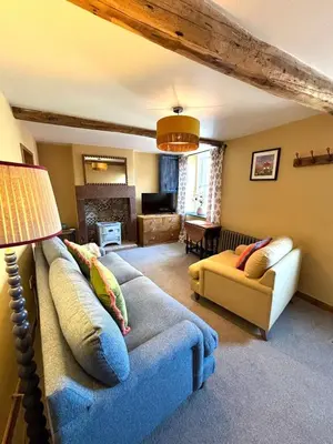 a living room with a blue couch and a chair at Maggies Cottage in Little Broughton
