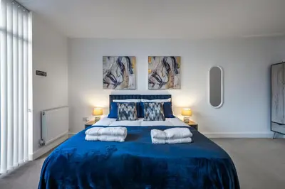 a bedroom with a blue bed with towels on it at Modern 2-Bed Flat with Balcony and Free Parking - Ideal for Contractors in Moffat