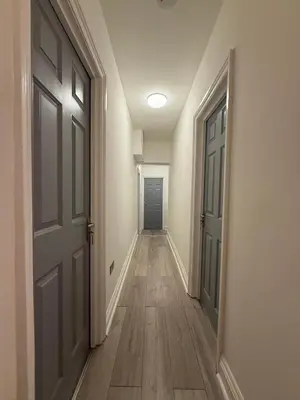 an empty hallway with an open door and wooden floors at Cosy Greenwich Flat Near -Cutty Sark, River & Park in Moffat