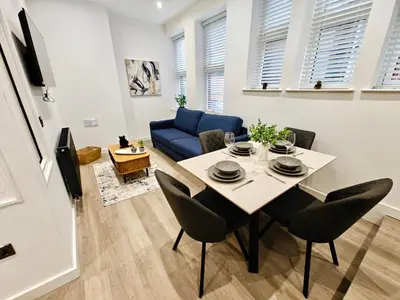 a living room with a table and a blue couch at Bright 2-Bed Apartment in Bury Town Centre in Moffat