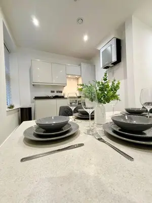 a kitchen with a table with plates and wine glasses at Bright 2-Bed Apartment in Bury Town Centre in Moffat