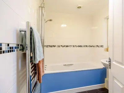 a bathroom with a white tub and a blue sink at 3 Bed in Holmrook oc-sz537 in Beckfoot