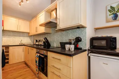 a kitchen with wooden cabinets and a microwave at South Loft a Modern Apartment in Cockermouth in Cockermouth