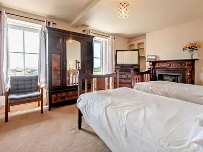 a bedroom with two beds and a chair and a fireplace at 3 Bed in Maryport oc-sz102 in Allonby