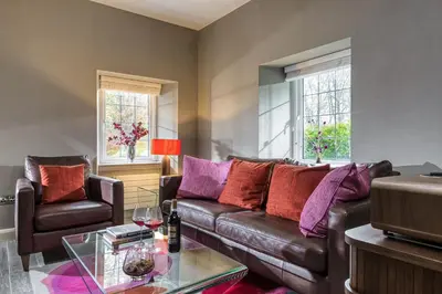 a living room with a leather couch and a glass table at Gate Lodge in Castle Douglas