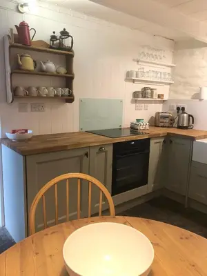 a kitchen with a table and a stove and a counter at Romantic Cottage, Port Isaac in Moffat