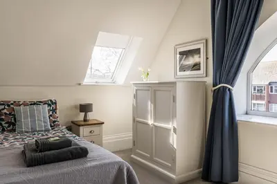 a bedroom with a bed and two windows at Old School Mews - Shanklin - Dog Friendly in Moffat