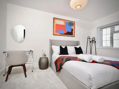 a white bedroom with a bed and a chair at Premium 4BR I Near Golf Course I Fast Wi-Fi & Free Parking in Moffat