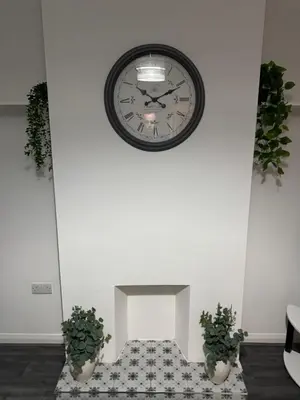 a clock on a wall with two potted plants at Rowe Terrace Workington in Workington