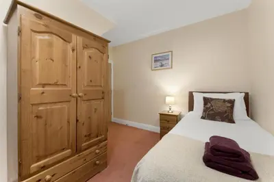 a bedroom with a bed and a wooden cabinet at 1 Harney Peak in Portinscale