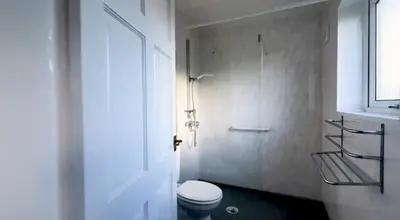 a white bathroom with a toilet and a shower at Pecklewell lodge in Ellenborough