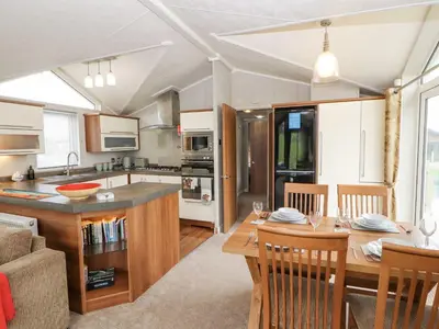 a kitchen and living room with a table and a dining room at No 8 Hillcote Lodge in Cockermouth