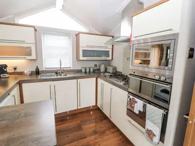a kitchen with white cabinets and stainless steel appliances at No 8 Hillcote Lodge in Cockermouth