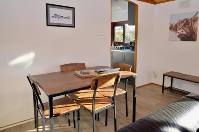 a dining room with a table and chairs and a kitchen at Lodge Cabin with Fabulous Views 2 - Farm Stay in Portpatrick