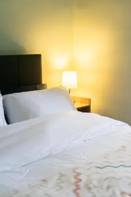 a bedroom with a white bed with a lamp on a table at The Woodrouffee retreat in Carlisle