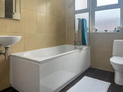 a bathroom with a tub and a toilet and a sink at Lakes And Shores Retreat in Maryport