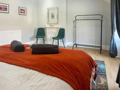 a bedroom with a bed with two green chairs at Lakes And Shores Retreat in Maryport