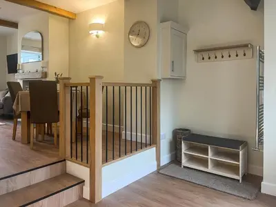 a living room with a staircase and a clock on the wall at Garth Cottage in Keswick