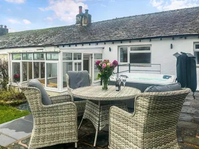 a patio with a table and chairs and a tub at Garth Cottage in Keswick
