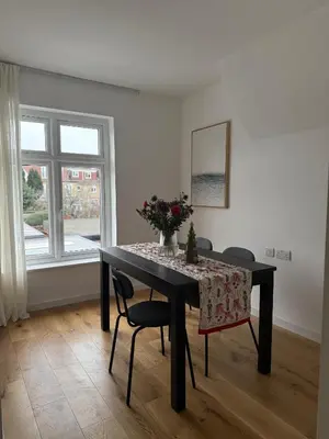 a dining room table with a vase of flowers on it at Private Rooms Near Acton Main Line Direct Elizabeth Line to Heathrow in Moffat
