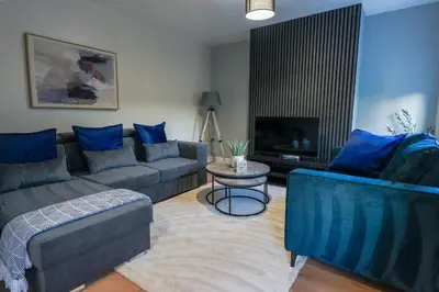 a living room with blue couches and a television at Victory House in Gretna